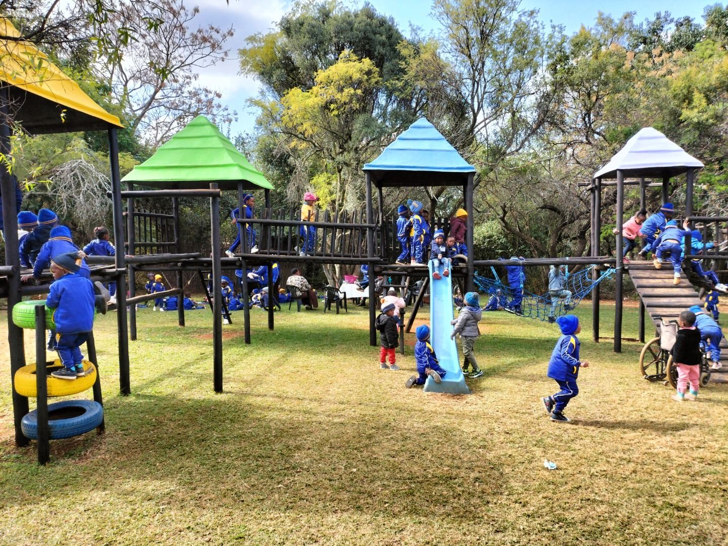 School children in blue tracksuits climbing the jungle gyms